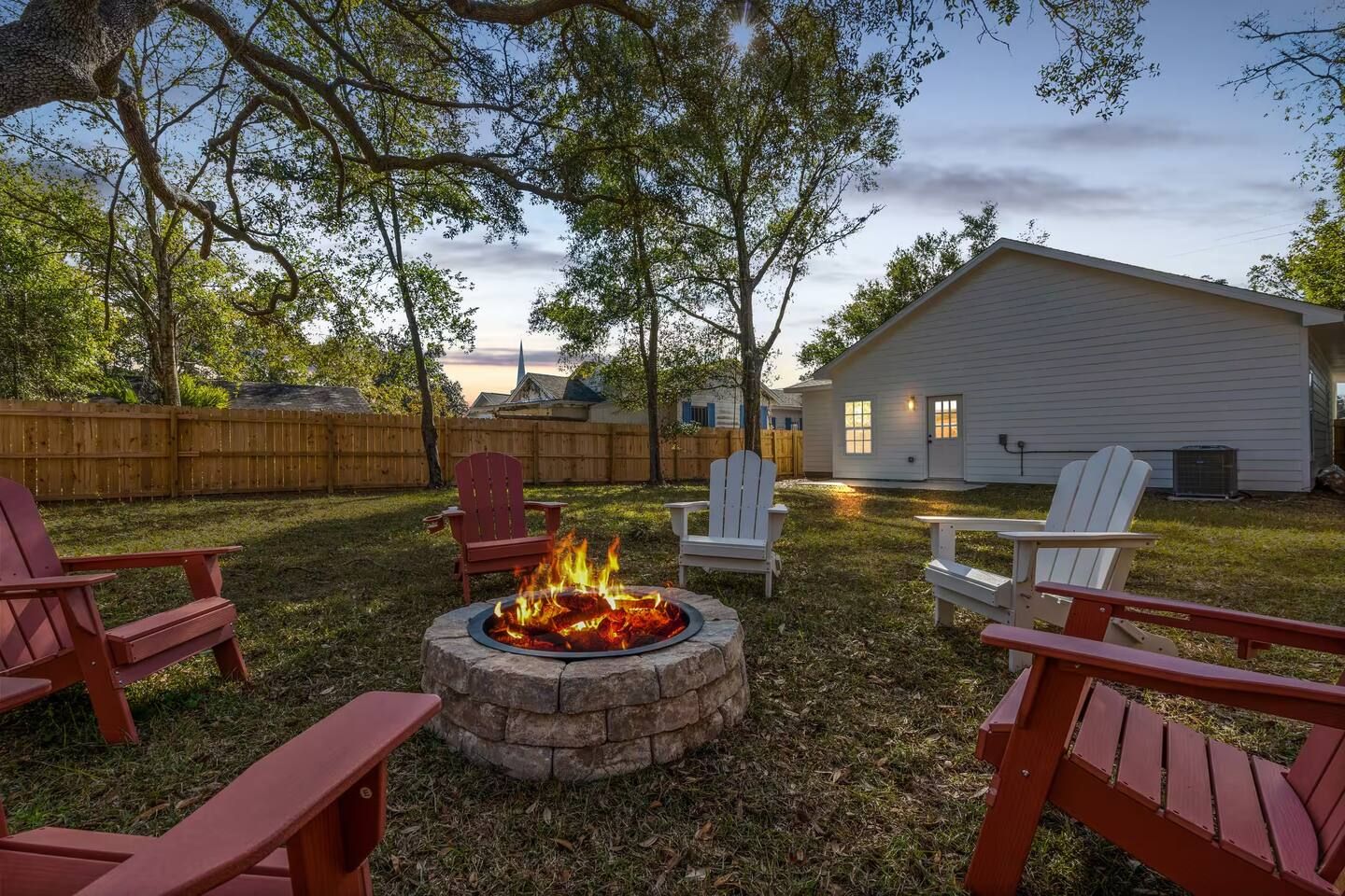 A backyard with a fire pit, outdoor seating, and a house.