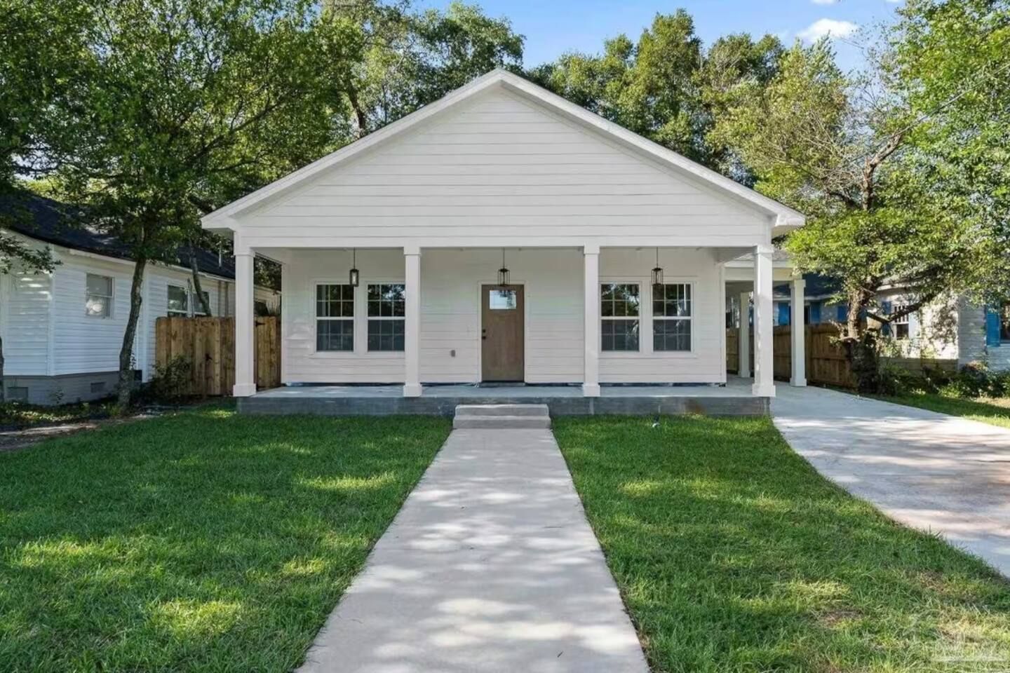 A single-story house with a front porch, a central door, and a small front yard.