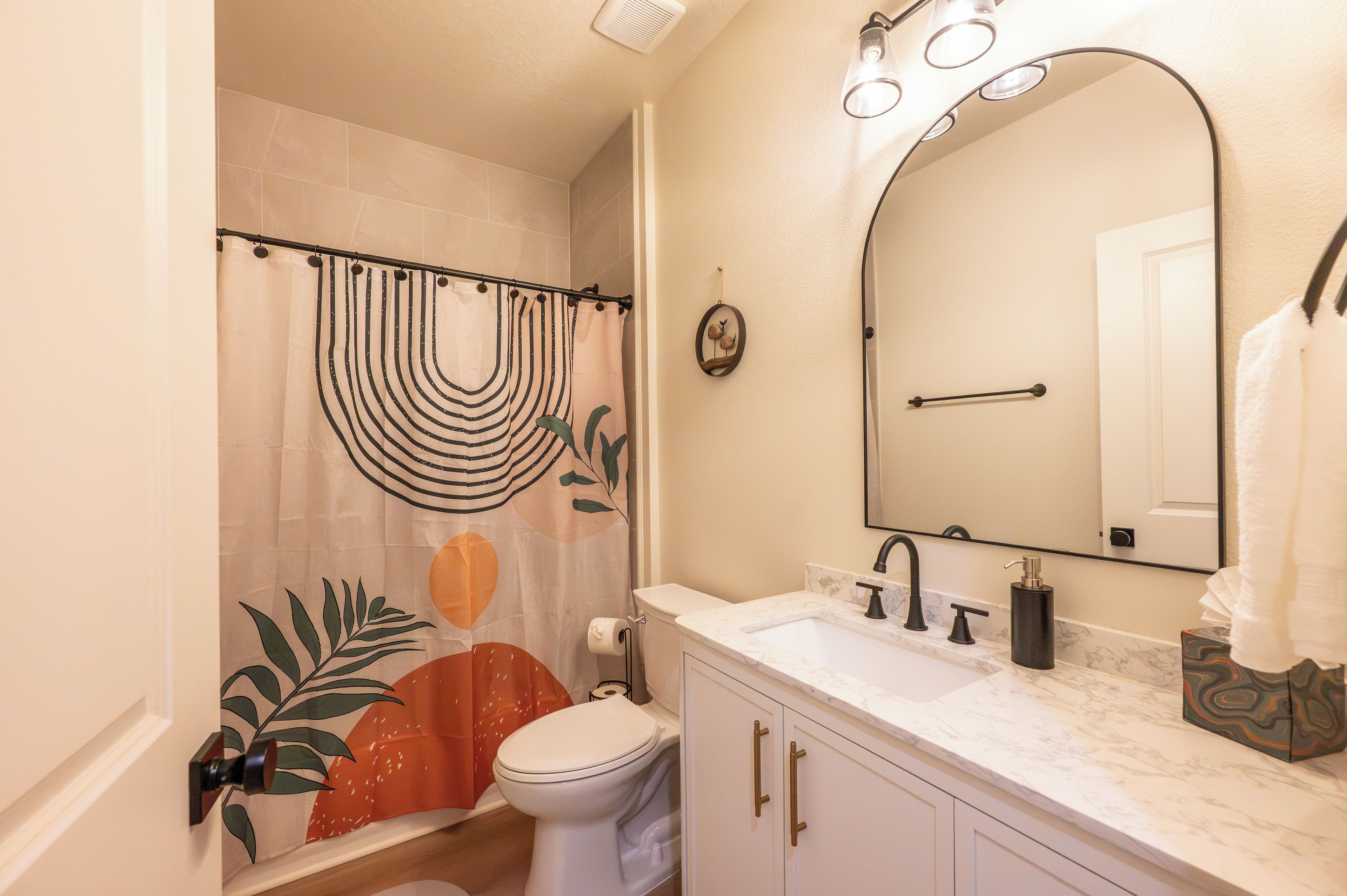 A bathroom with a toilet, sink, mirror, and shower curtain.