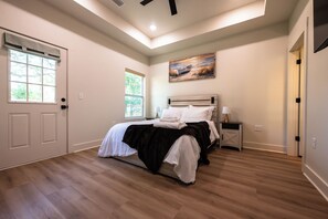 A bedroom with a bed, a nightstand, a painting, and a door.