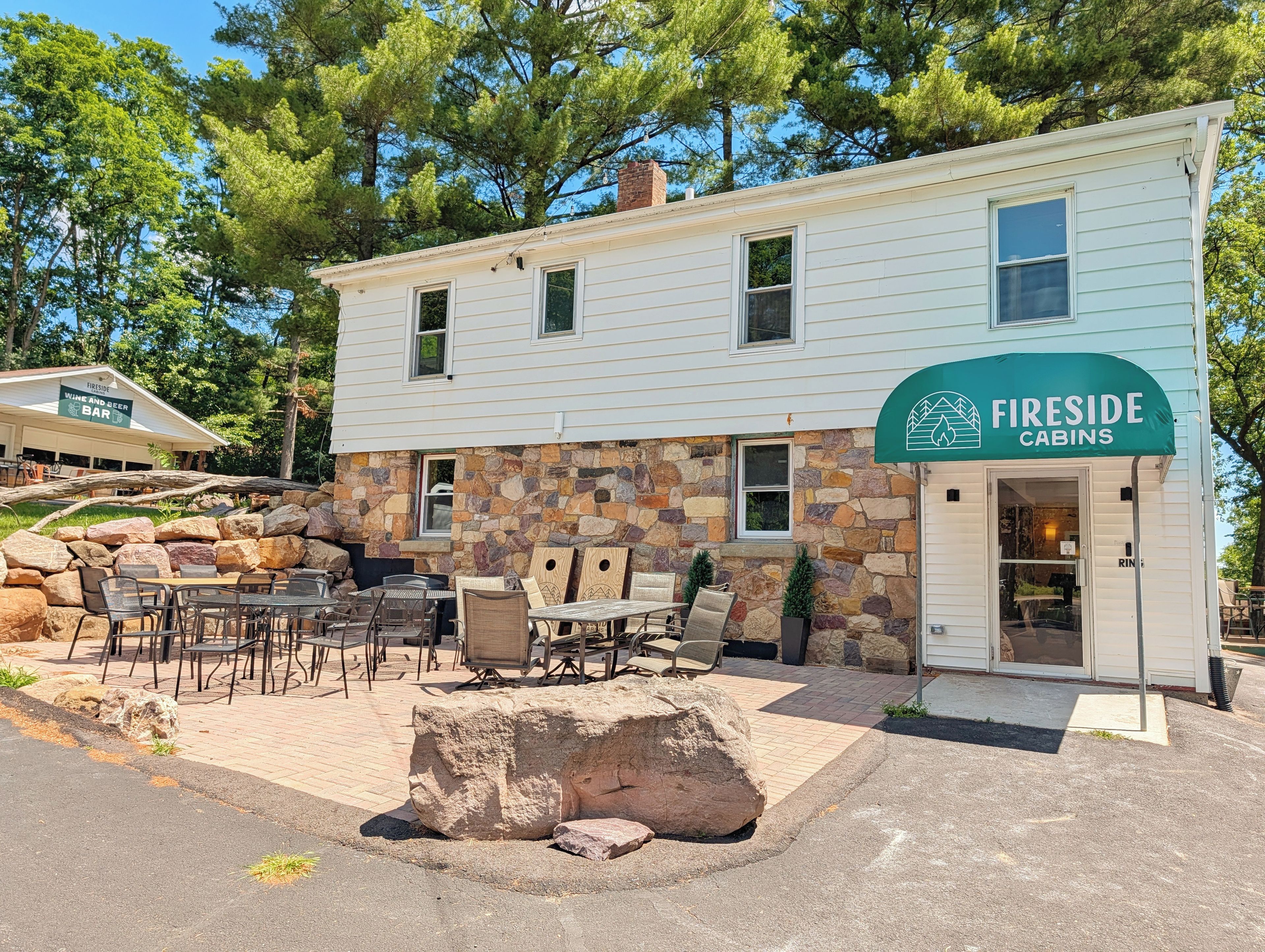 A cabin with a stone facade, outdoor seating, and a sign for Fireside Cabins.