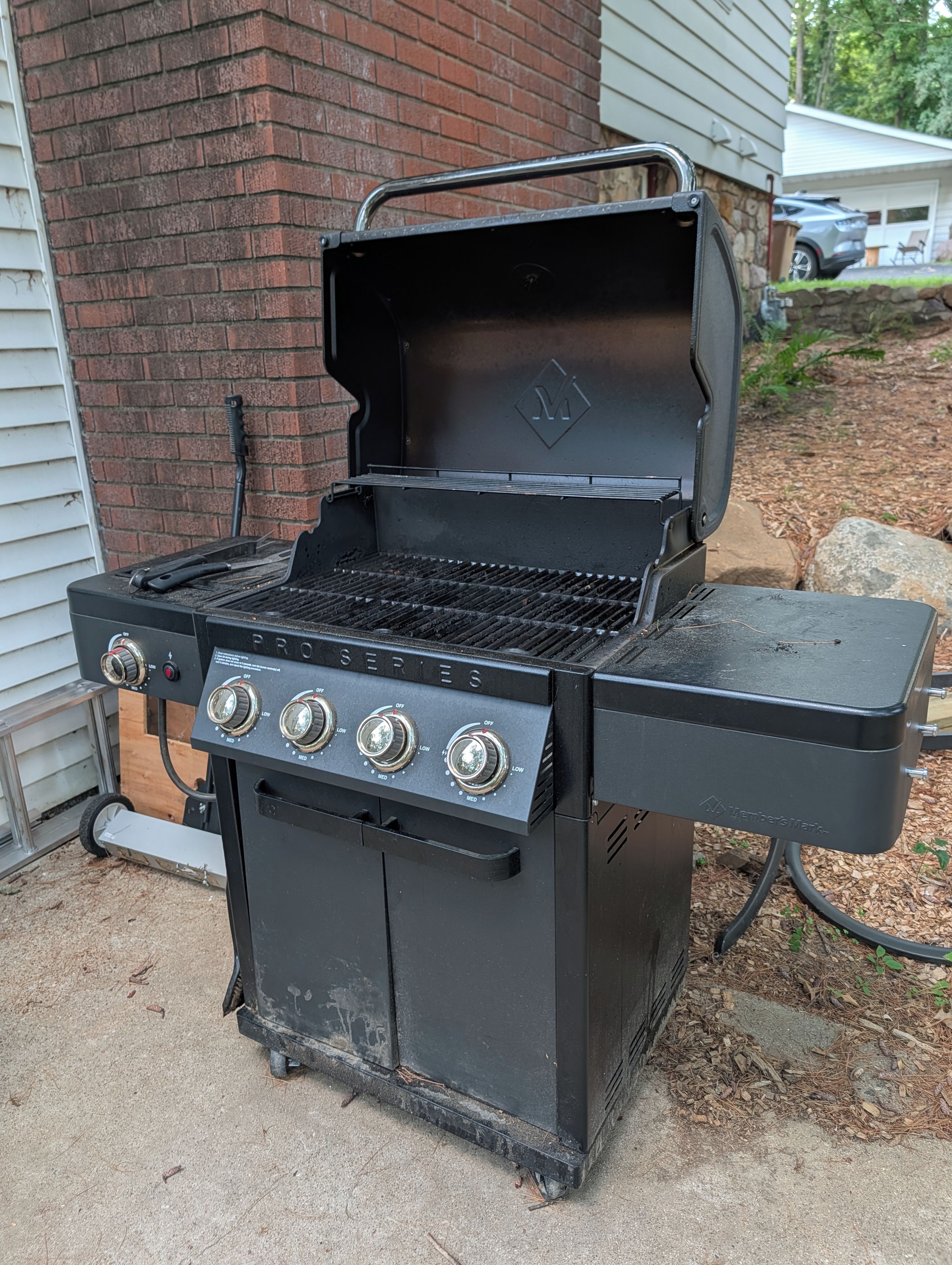 Un barbecue noir de la série Weber's Mark, doté de quatre brûleurs, d'une étagère latérale et d'une cheminée.