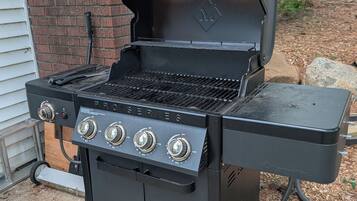 Un barbecue noir de la série Weber's Mark, doté de quatre brûleurs, d'une étagère latérale et d'une cheminée.