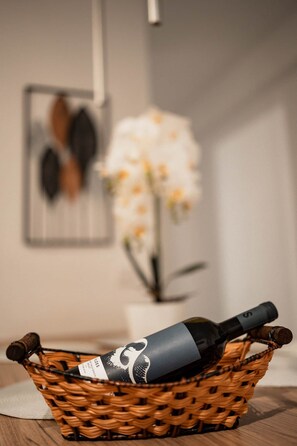 Una cesta de mimbre con una botella de vino sobre una mesa de madera.