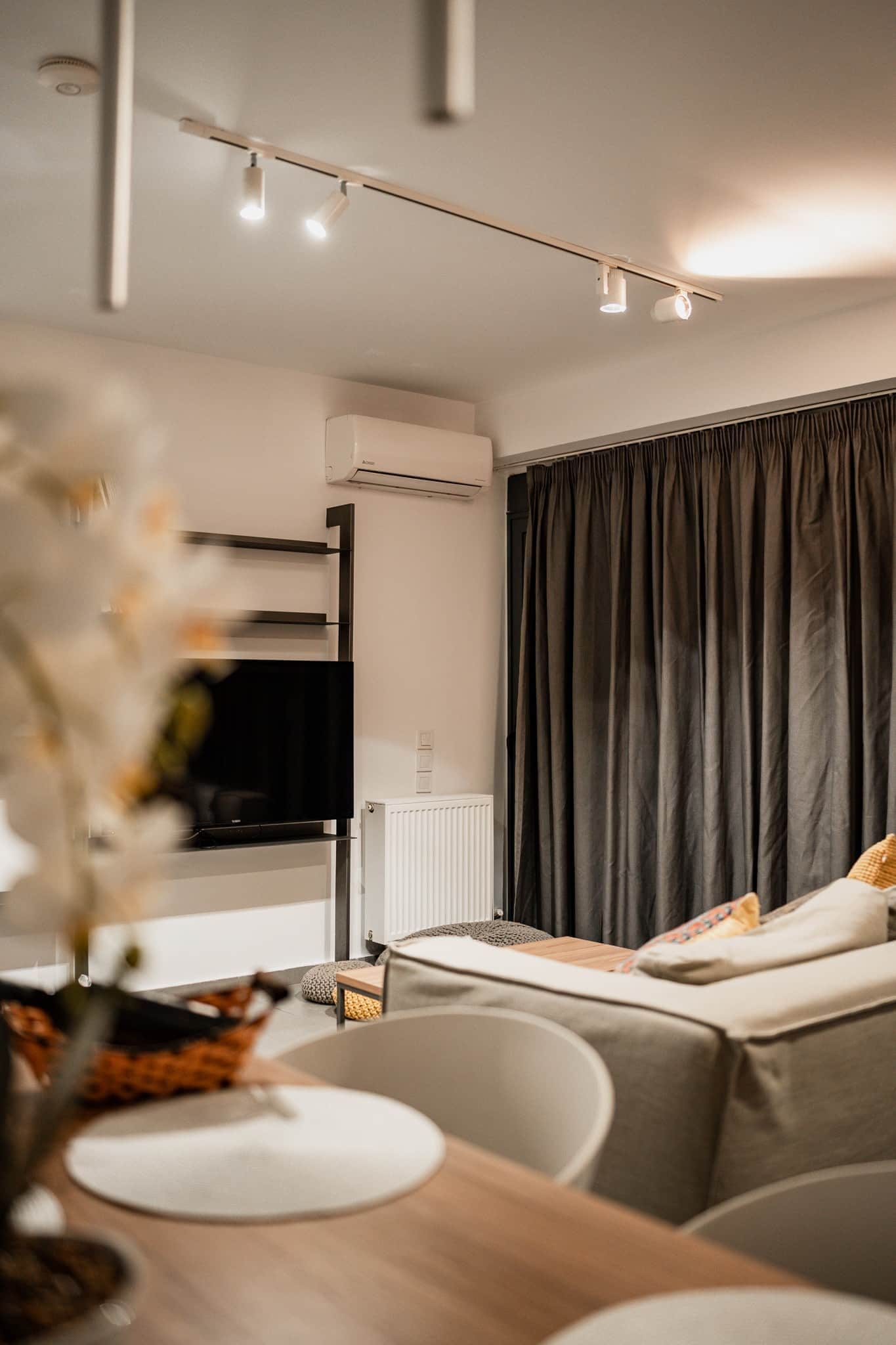 Habitació d'hotel moderna amb zona de menjador, televisió de pantalla plana i finestra gran amb cortines.