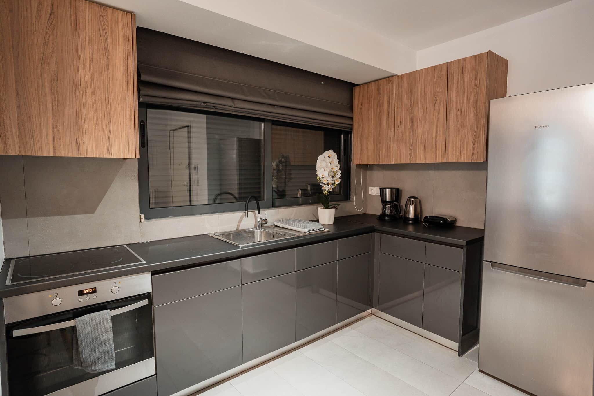 Una cucina moderna con forno integrato, frigorifero in acciaio inox e una finestra vista.