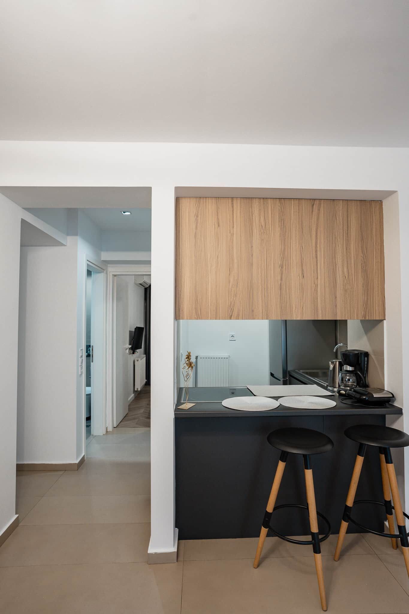 Una cucina moderna con un piano di lavoro nero, mobili in legno e due sgabelli neri.