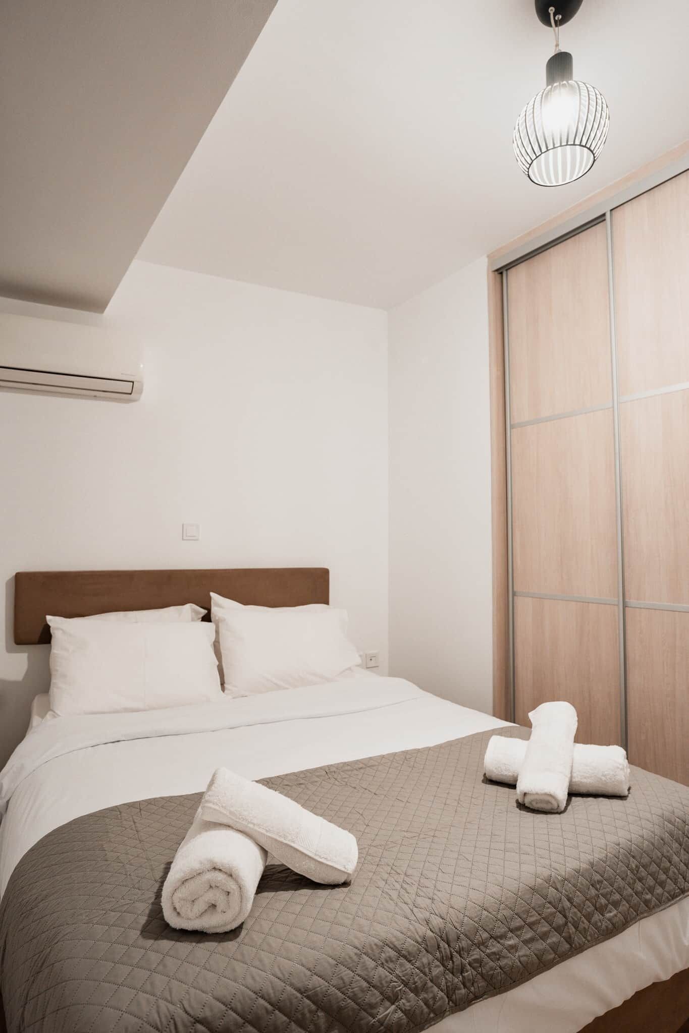 Una camera d'albergo con un letto, una finestra e una lampada a sospensione.