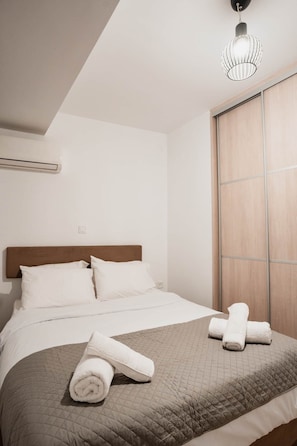 Una camera d'albergo con un letto, una finestra e una lampada a sospensione.
