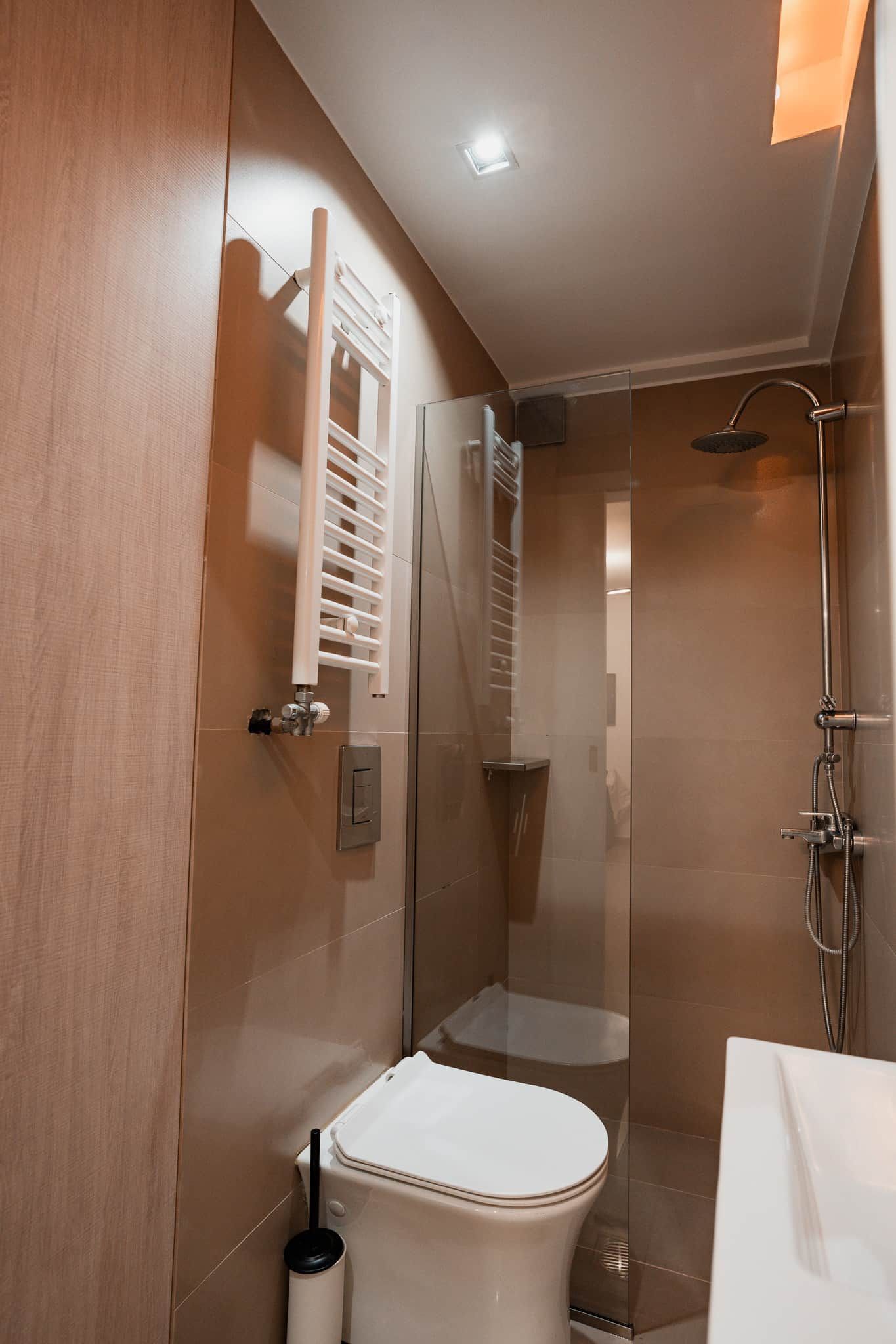 Casa de banho moderna com cabine de duche envidraçada, sanita e suporte para toalhas.