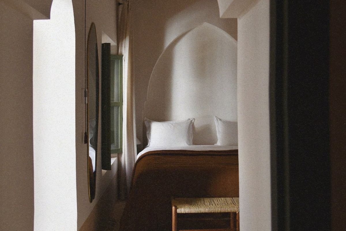 A bedroom with a bed, a bench, and a mirror.