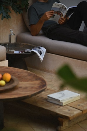 A person reading a magazine on a sofa with a coffee table in front. - Neighbours Boutique Riad Marrakech (Marrakech)