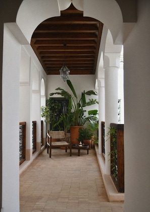A covered patio area with a wooden bench, potted plants, and a hanging light fixture. - Neighbours Boutique Riad Marrakech (Marrakech)