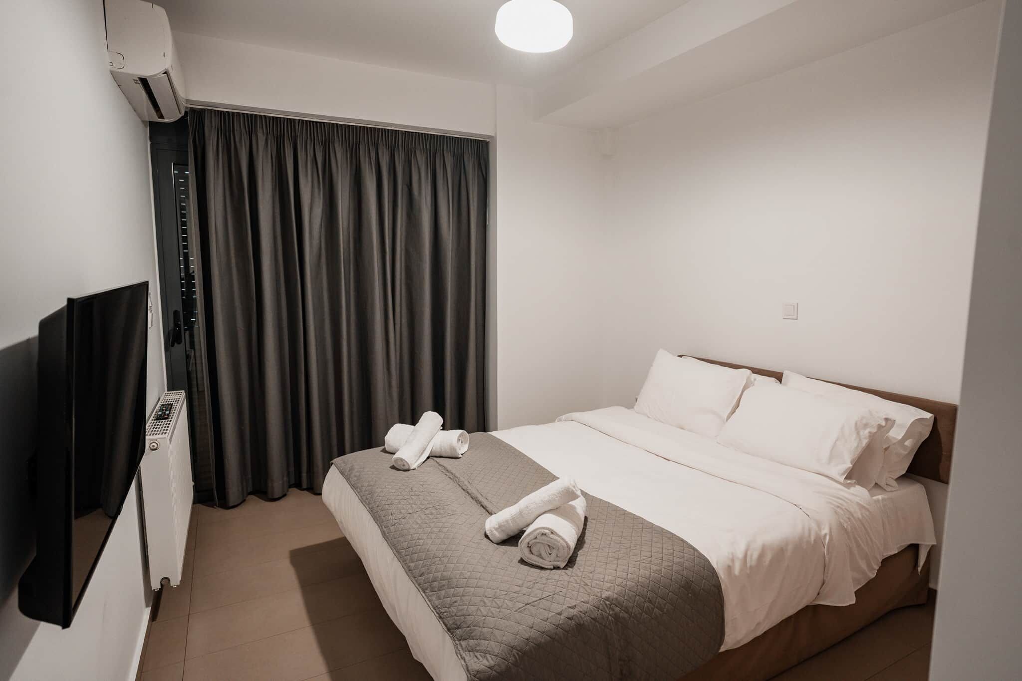 Una camera d'albergo con un letto, una scrivania, una sedia e una finestra con tende.