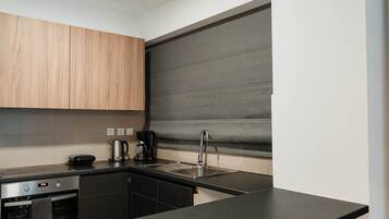 Una cucina moderna con un piano di lavoro nero, mobili in legno, forno integrato e schienale grigio.