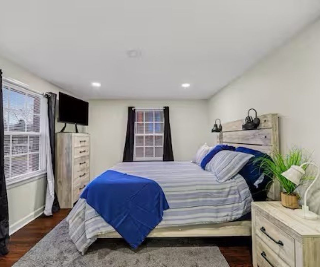 A bedroom with a bed, a dresser, a television, and a window.