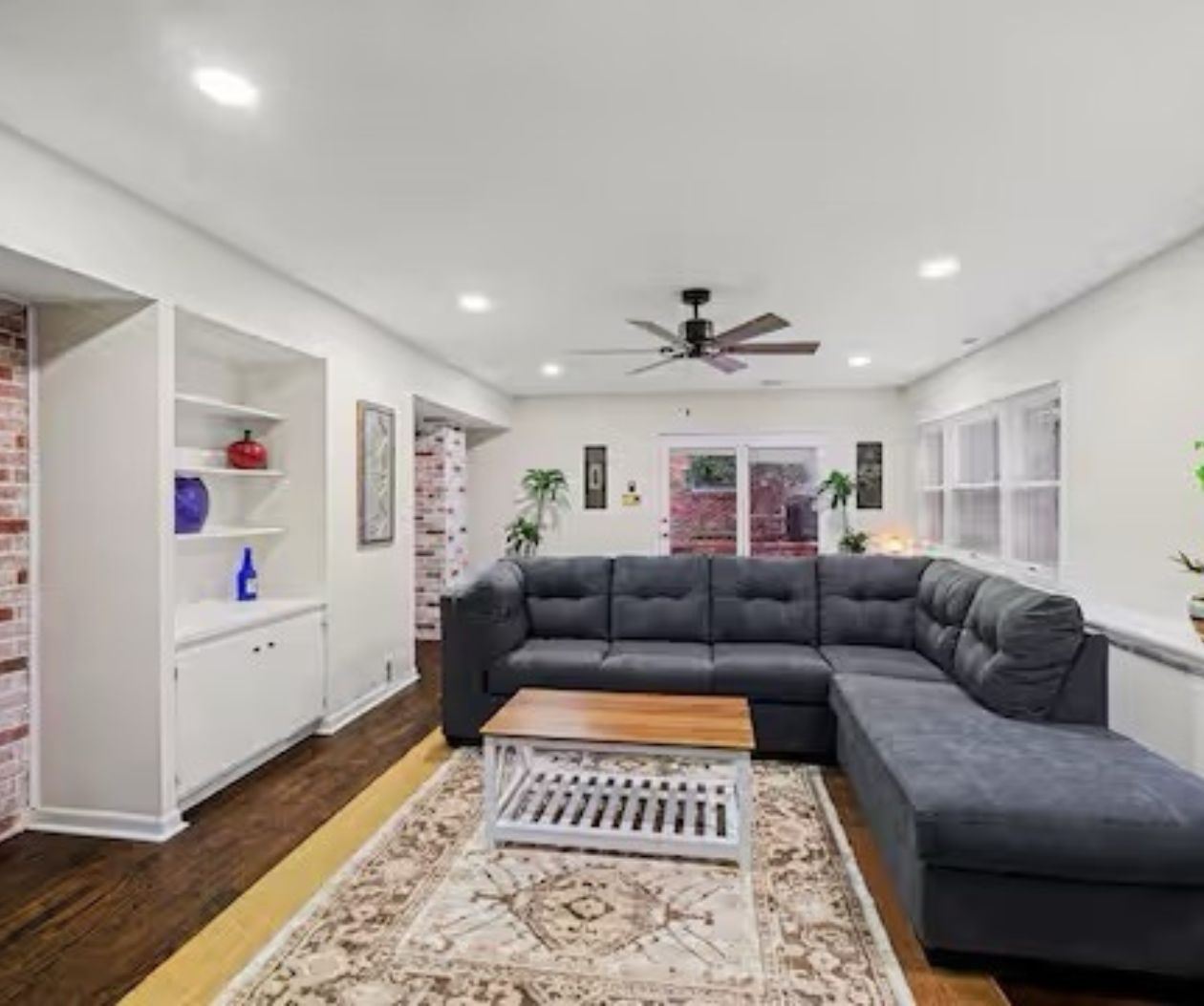 A modern living room with a sectional sofa, a coffee table, and a white shelving unit.