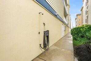 Ein schmaler Gang mit einem Wasserschlauch und einem Wasserzähler an der Wand.