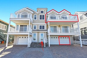 A multi-story residential building with a central entrance, two balconies on the upper floor, and a garage on the ground level. - Bay-view 3BR/2BA Condo with balcony (Wildwood Crest)