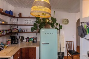 Eine Küche mit einem vintage-Kühlschrank in hellblau, einer hängenden Lampenschirm aus Weidengeflecht und einer Uhr an der Wand.