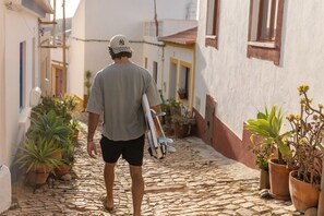 A person walking down a cobblestone street with potted plants on either side. - Casa do Cacto, a cozy house with fast Wi-Fi and a large, sunny terrace!! (Budens)