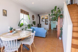Een eethoek met een ronde tafel, stoelen en een potplant.