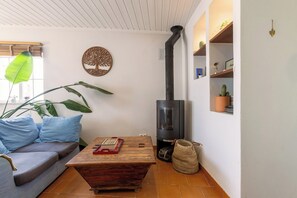 A cozy living room with a sofa, a wooden coffee table, a wall-mounted heater, and a cactus on a shelf.