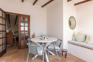 Ein Zimmer mit einem runden Tisch, zwei Stühlen, einer Bank und einem Wandspiegel.