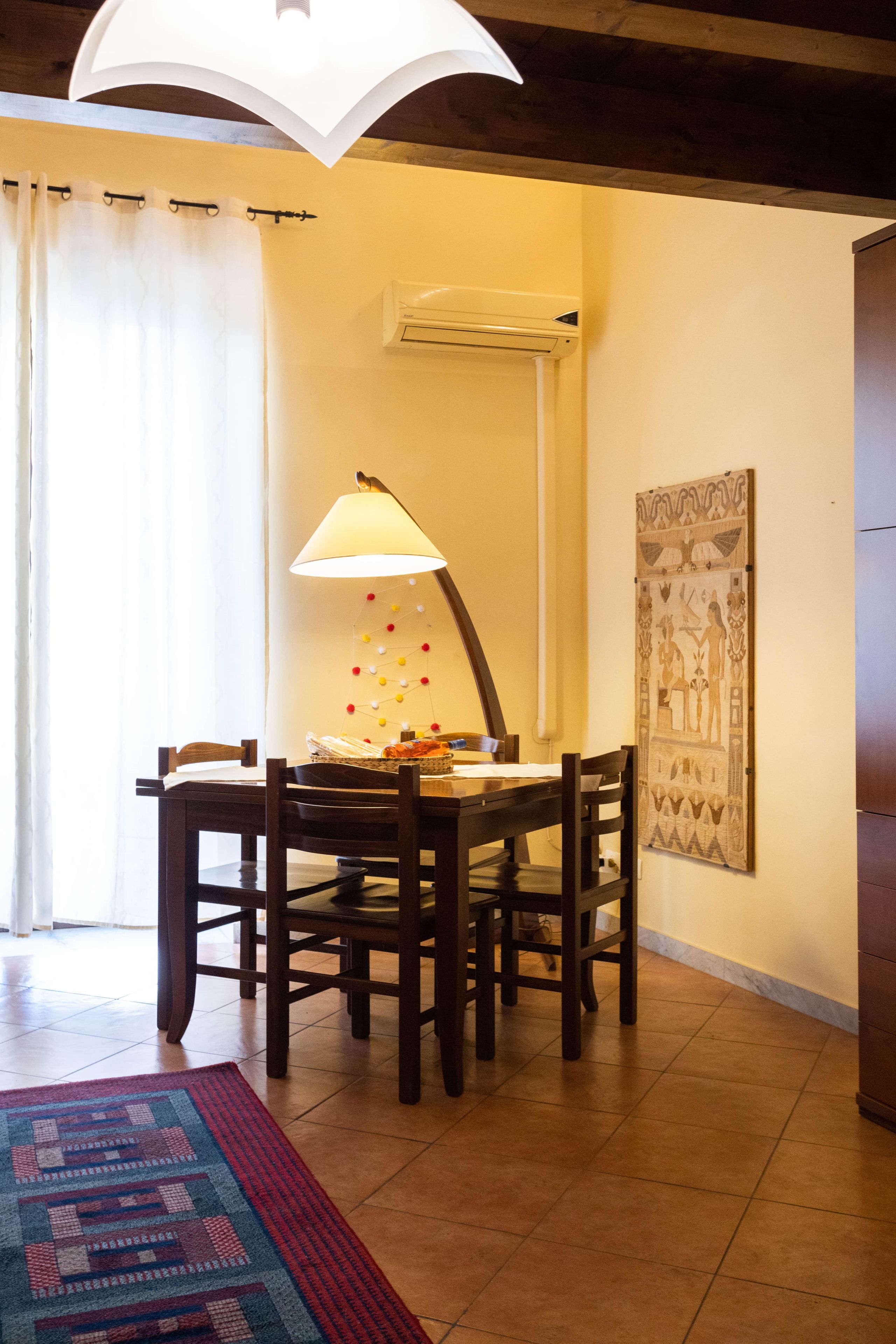 Un coin repas comprenant une table, des chaises, une lampe et un climatiseur fixé au mur.