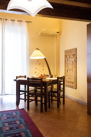 Un coin repas comprenant une table, des chaises, une lampe et un climatiseur fixé au mur.