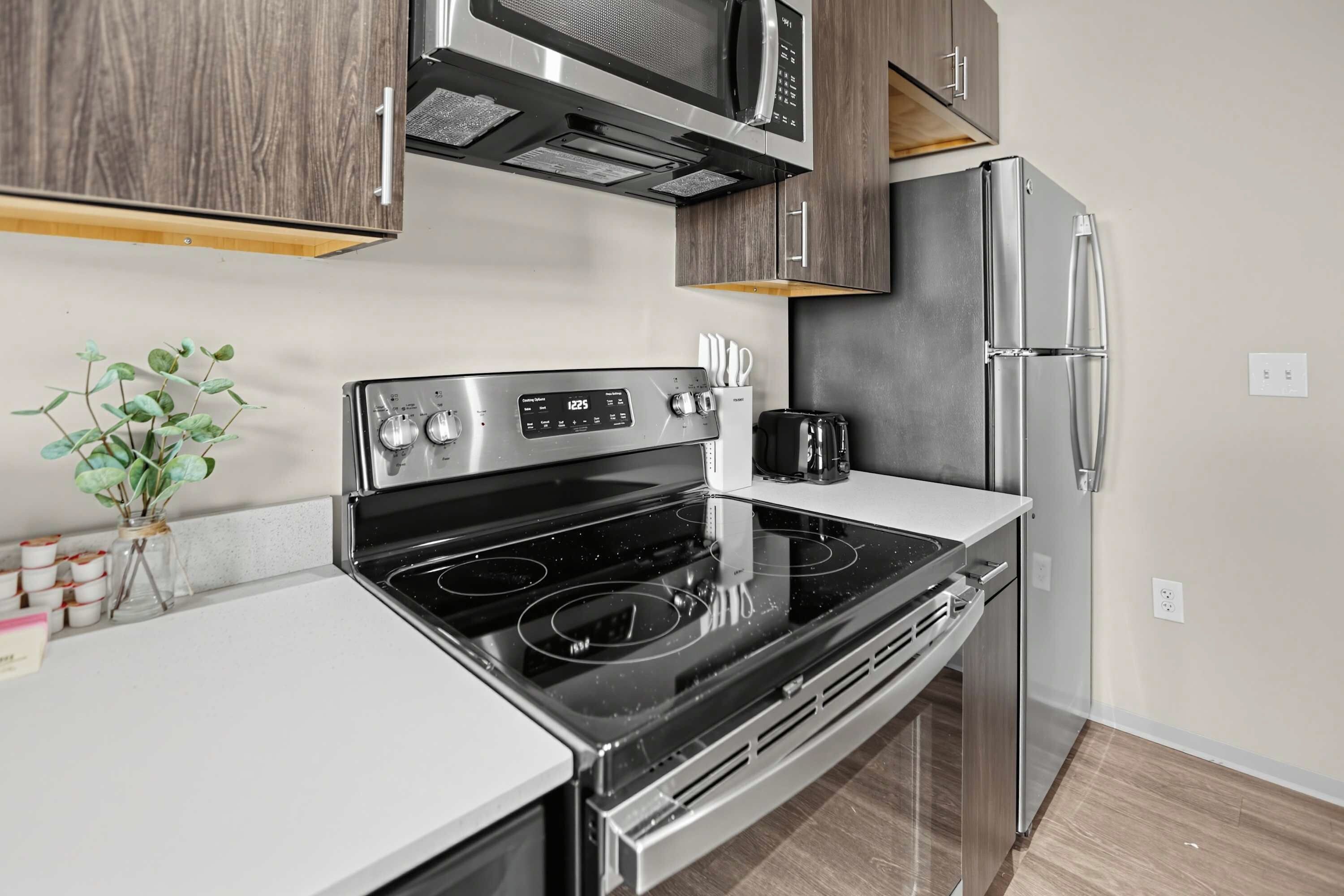 Una cocina moderna con estufa de acero inoxidable, microondas y refrigerador.