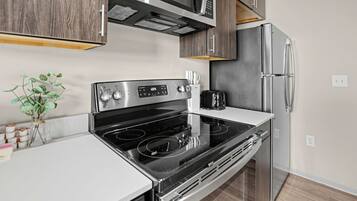 A modern kitchen with a stainless steel stove, a microwave, and a refrigerator.