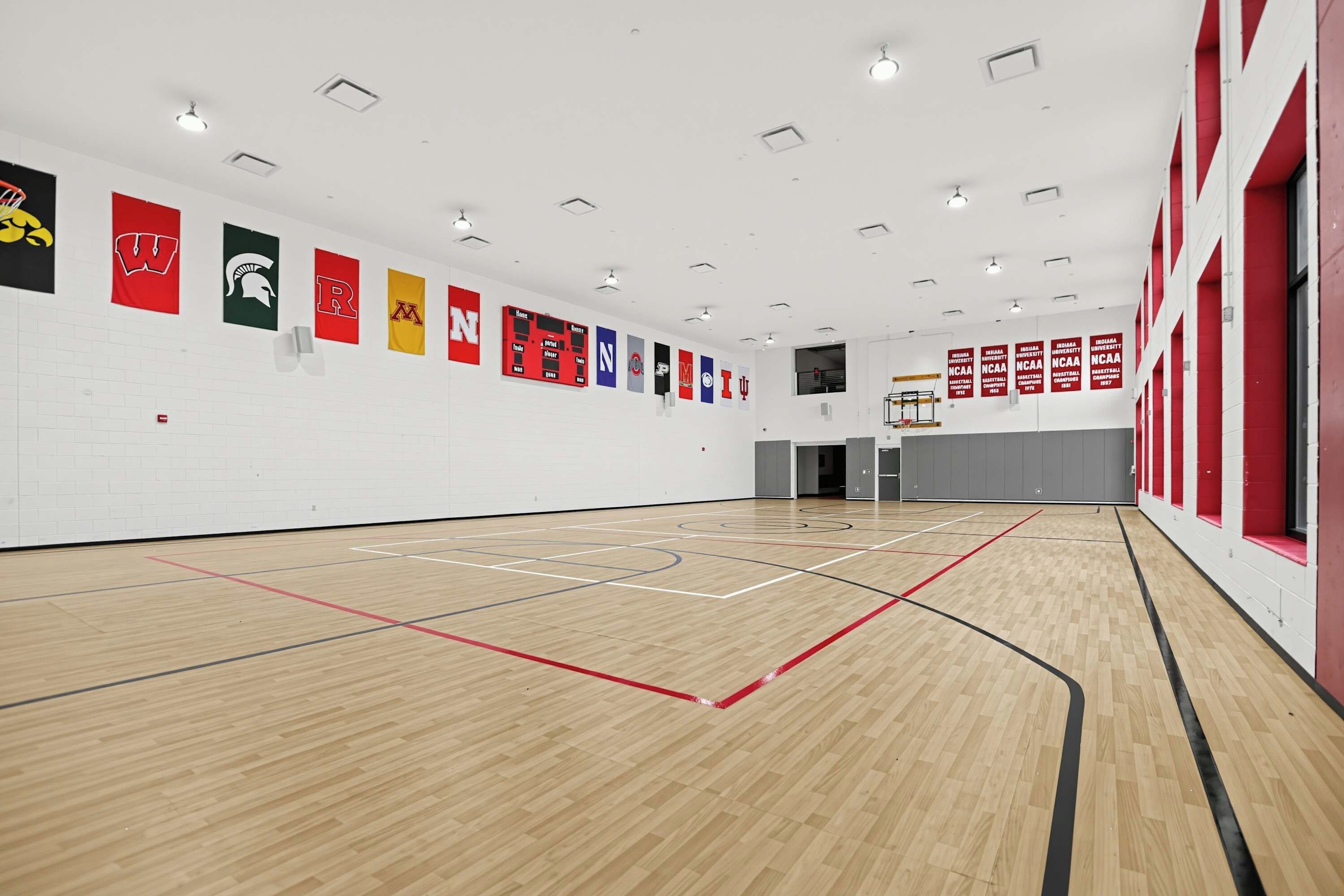 Una cancha de baloncesto interior con suelo de madera y varios banderines en las paredes.