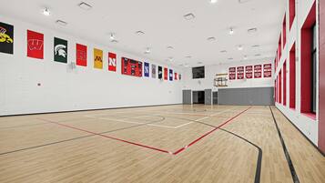An indoor basketball court with a wooden floor and multiple banners on the walls.