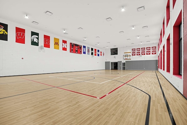Una cancha de baloncesto interior con suelo de madera y varios banderines en las paredes.