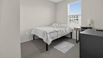 A bedroom with a bed, a nightstand, a lamp, and a window with blinds.