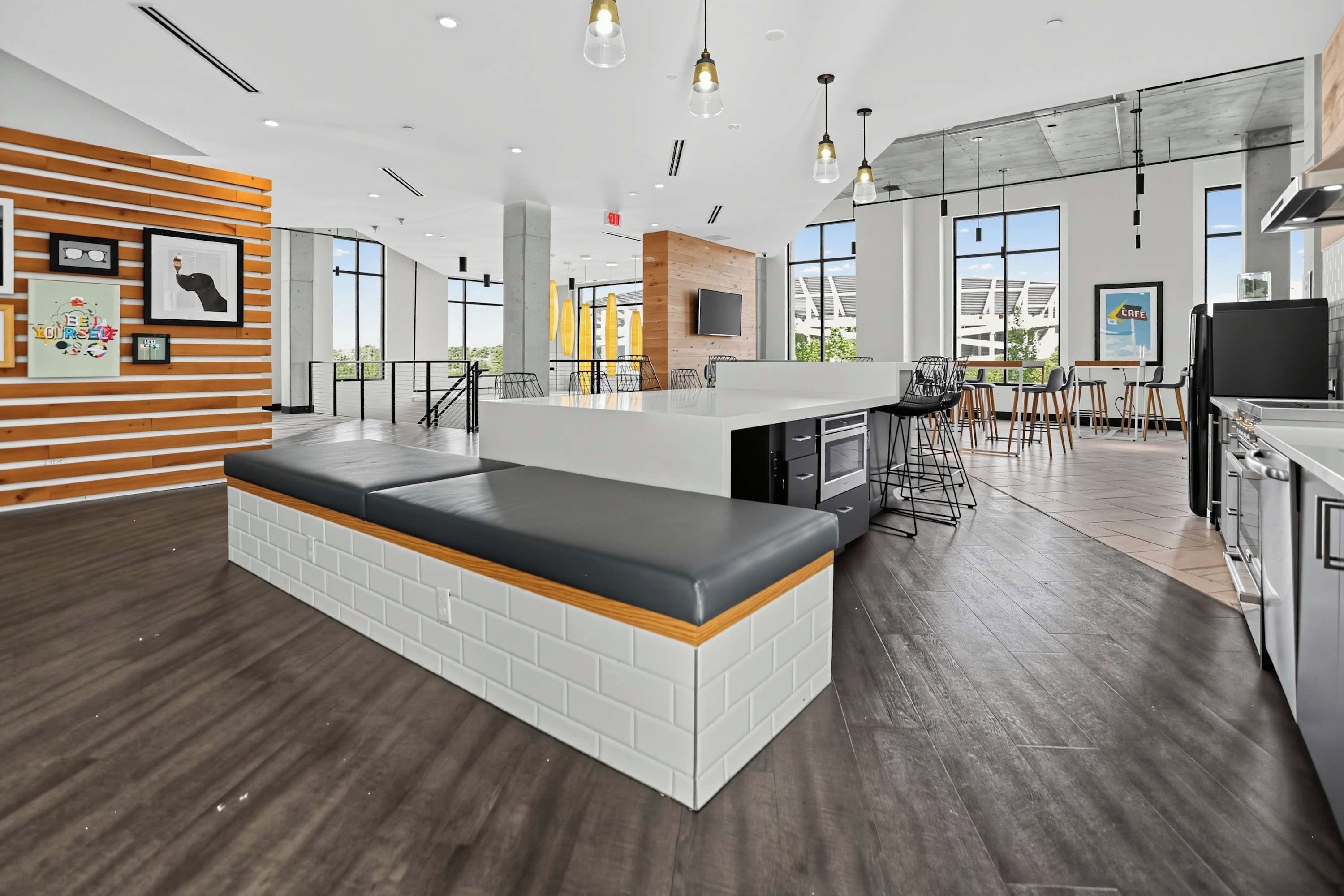A modern kitchen with a central island, bar stools, and a large window offering a view of the outdoors.