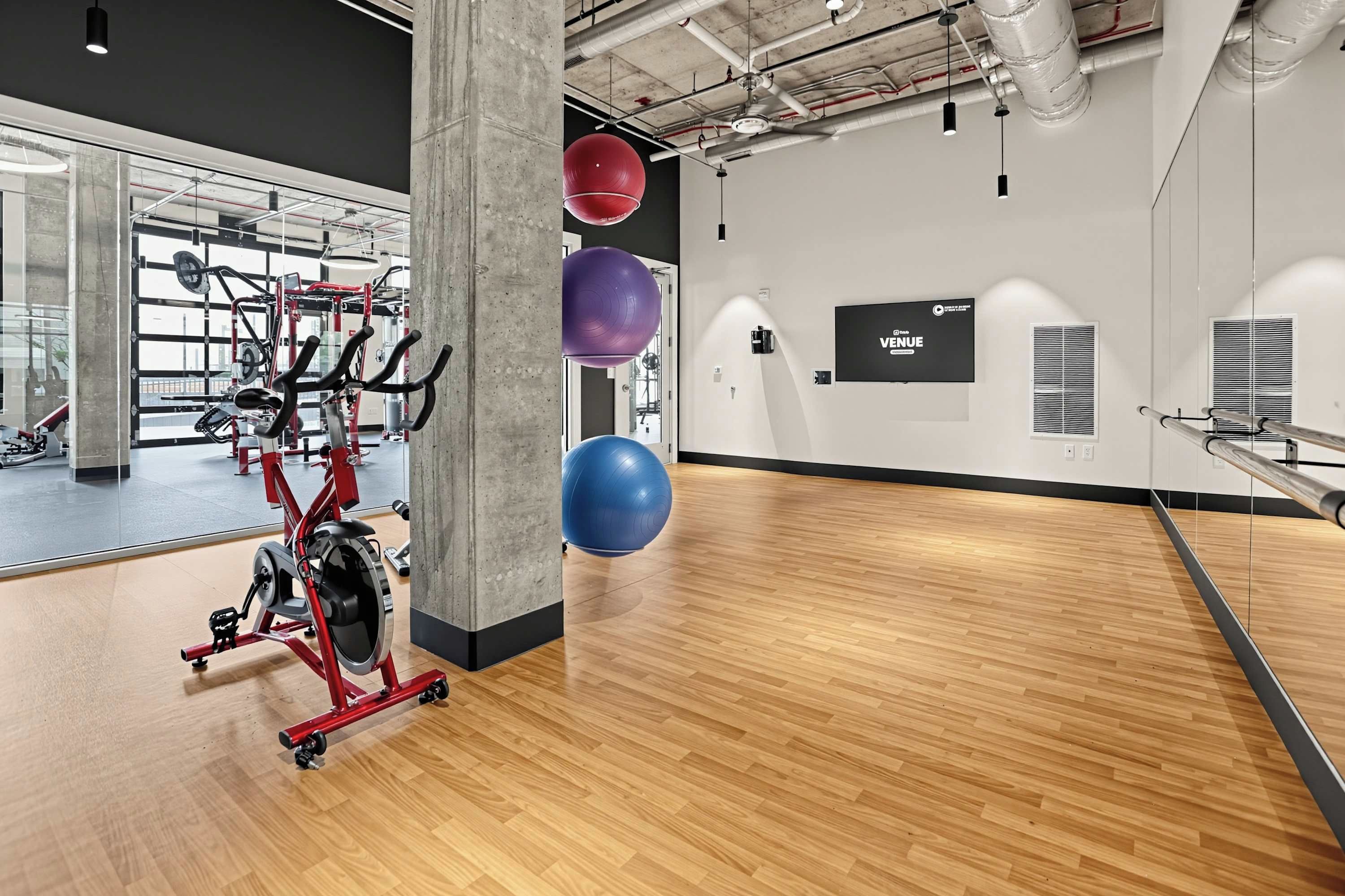 Un gimnasio con equipo de ejercicio, un espejo grande y pelotas de entrenamiento.