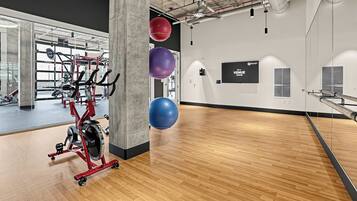 A gym with exercise equipment, a large mirror, and exercise balls.