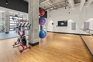 Un gimnasio con equipo de ejercicio, un espejo grande y pelotas de entrenamiento.