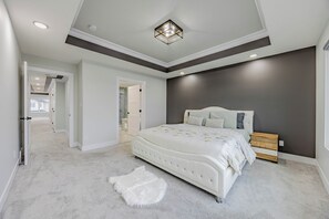 Ein Schlafzimmer mit einem großen Bett, einem weißen Fellteppich und einer dunkel gestrichenen Wand.