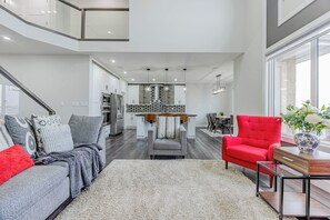 Ein stilvoller Wohnraum mit grauem Sofa, rotem Sessel und einer Küche im Hintergrund.