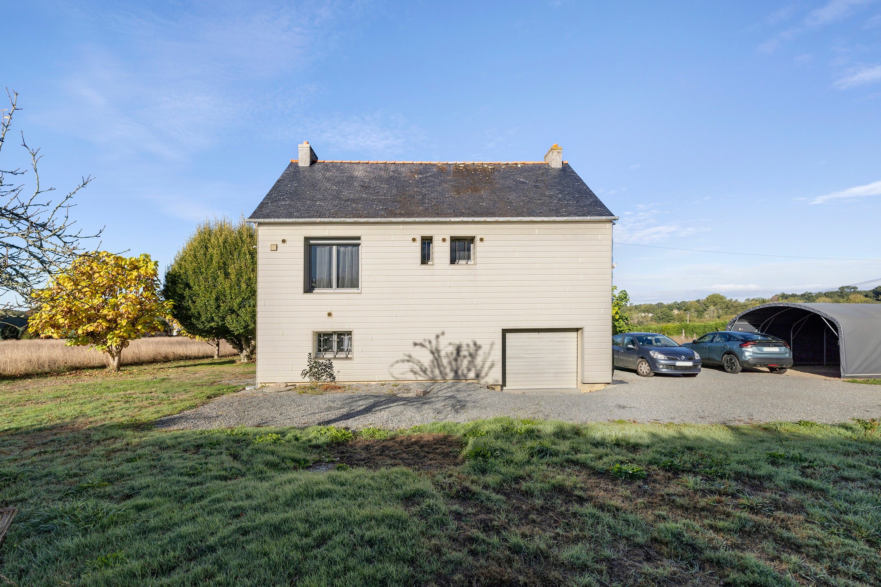 Einbungalow mit Garage, überdachtem Autostellplatz und Auffahrt mit Kies.