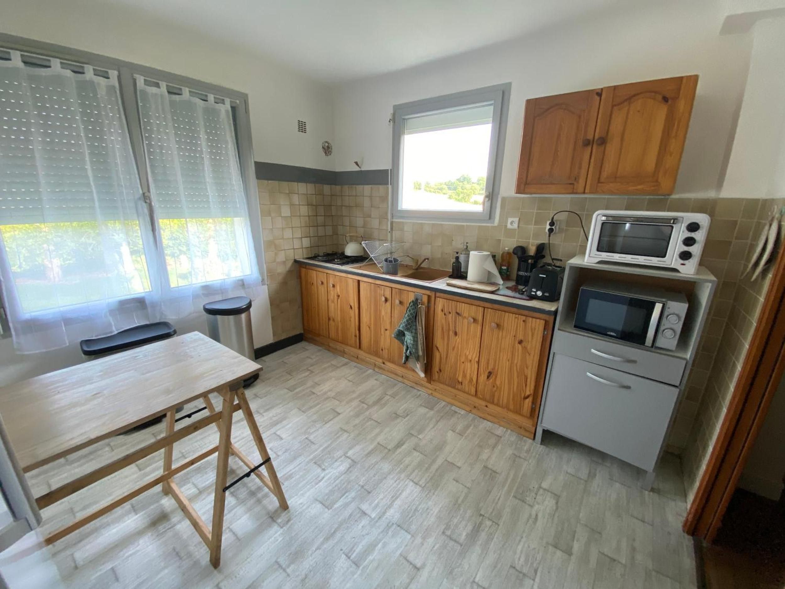 Una cocina compacta con armarios de madera, un microondas integrado y un ventanal que proporciona luz natural.
