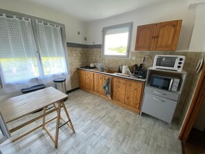 Una cocina compacta con armarios de madera, un microondas integrado y un ventanal que proporciona luz natural.