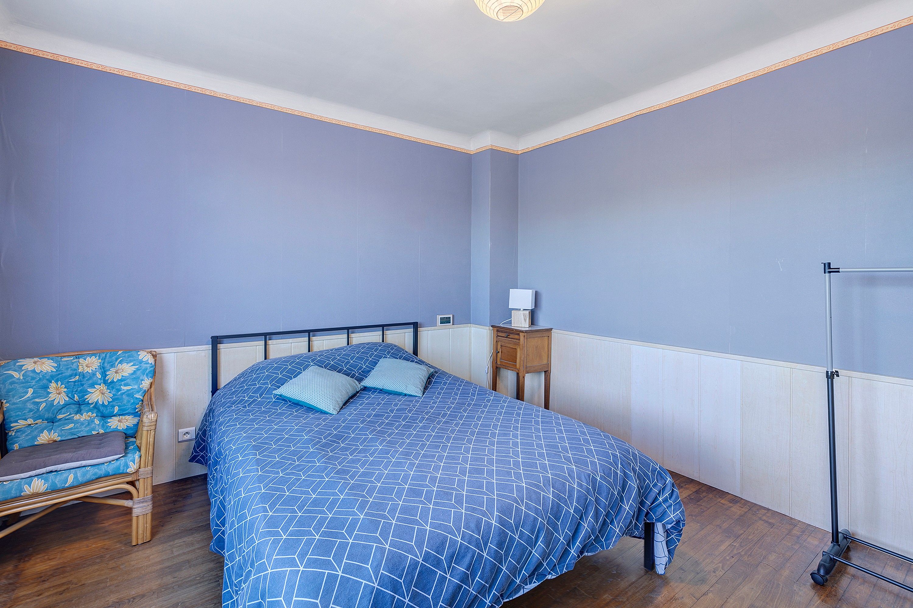 Une chambre à coucher comprenant un lit, une chaise, une table de chevet et une armoire.