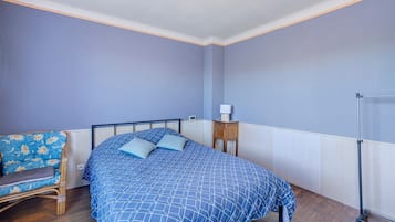 Une chambre à coucher comprenant un lit, une chaise, une table de chevet et une armoire.