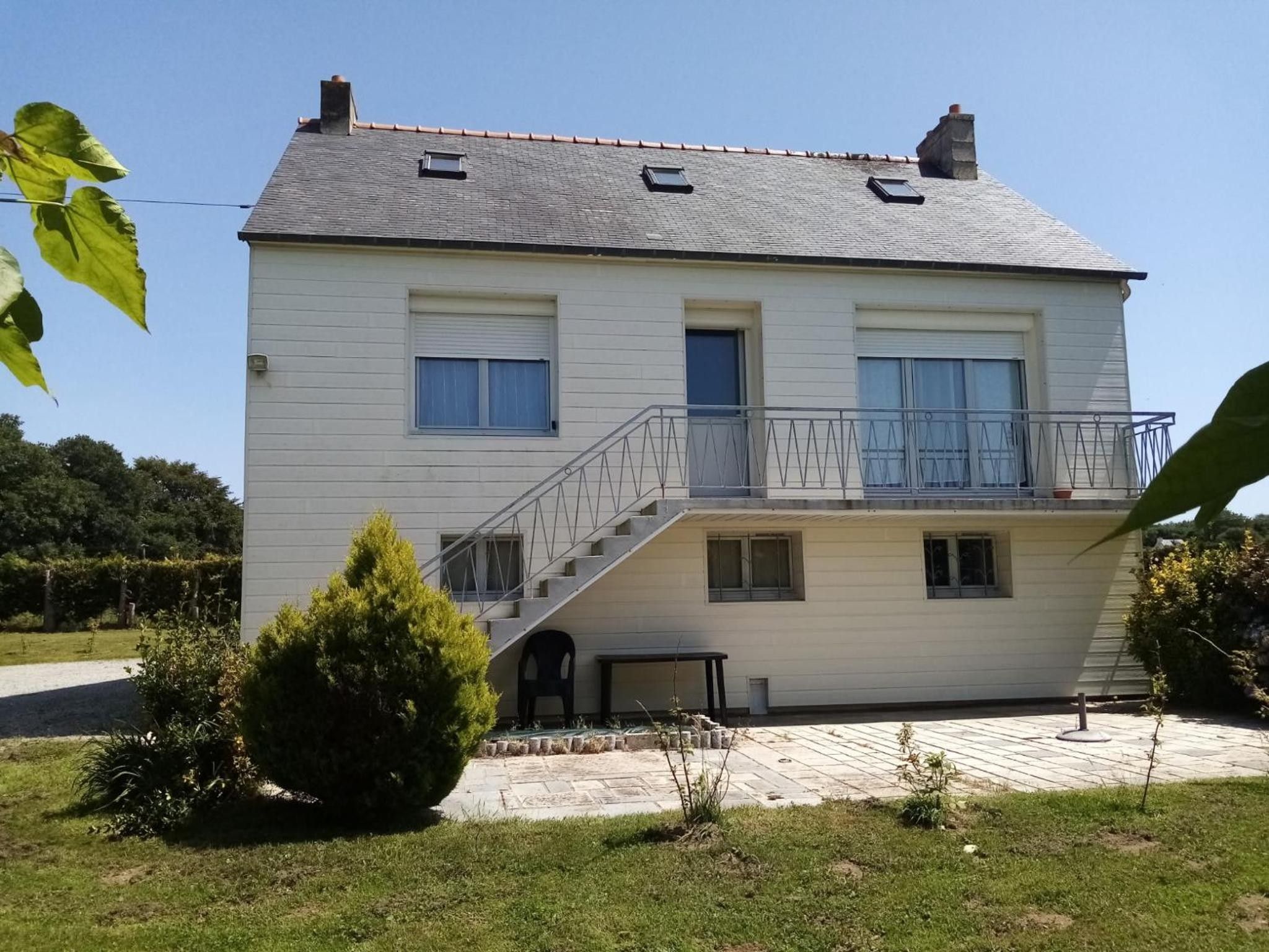 A two-story house with a balcony, a staircase leading to the upper floor, and a small garden area.