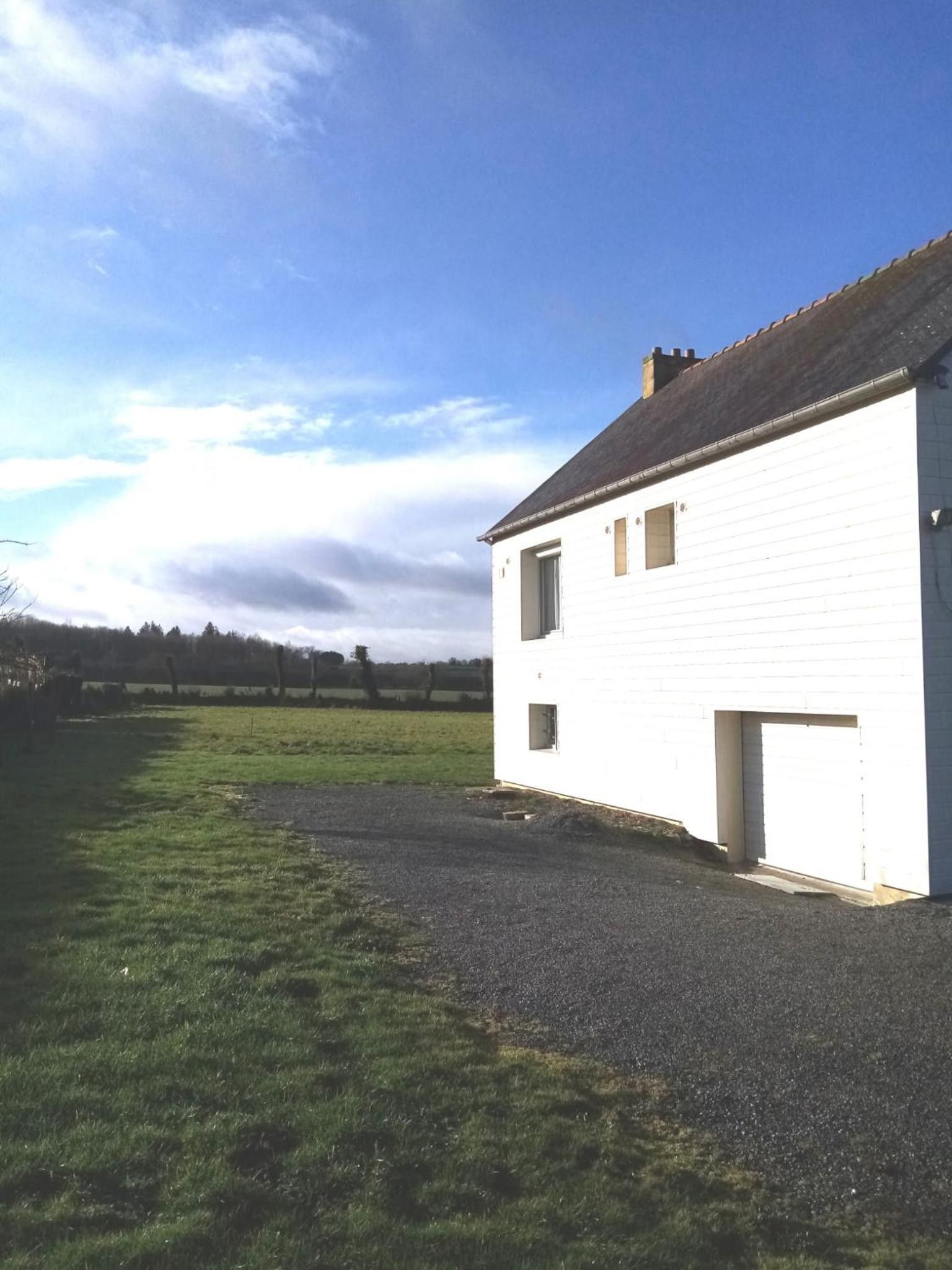 Un edificio blanco con un camino de grava y un campo verde al fondo.