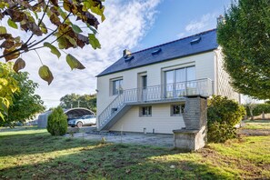 A two-story house with a covered carport, a stone staircase, and a small garden area.